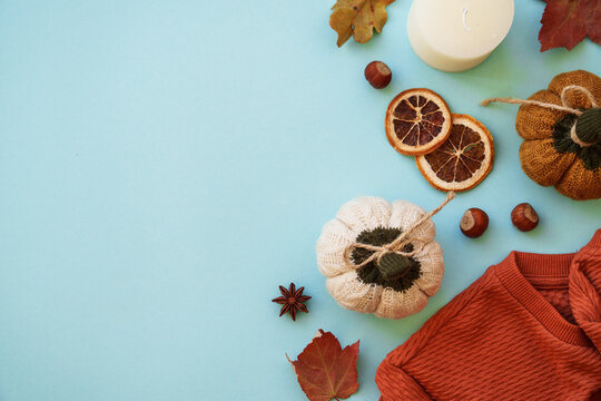 Warm sweater, autumn leaves, candle and decor on blue background. Flat lay image with copy space.