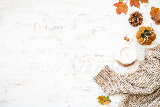 Cozy autumn background on white. Warm sweater, autumn leaves, candle and decor. Flat lay image with copy space.