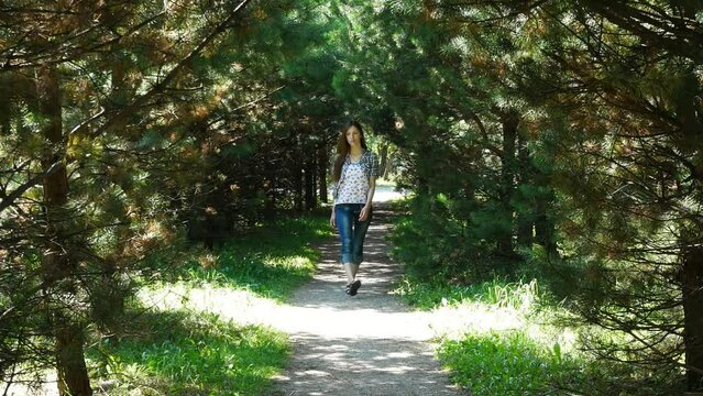 A cute girl walks along a beautiful forest path