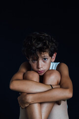 Portrait of a 10 year old boy looking sad, black background