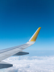 Vertical image, wing of a plane during the flight, blue sky on the background