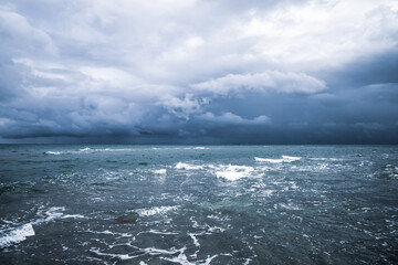 Dramatic seascape in dark colors. Dark sky with clouds over the stormy sea.