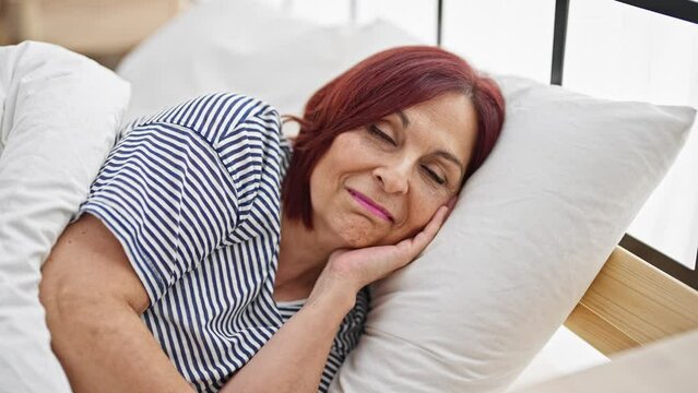 Middle age woman smiling confident lying on bed at bedroom