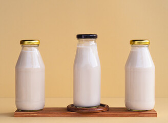 Organic soy milk in glass bottle on wooden planks on beige background. vegan product, Minimalist concept and Healthy drinks