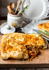 Puff pastry meat pie on a board, rustic style on the kitchen table..