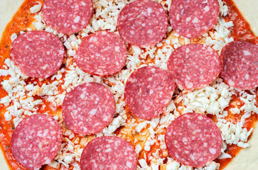 pizza preparation process, sliced salami sausage, close-up