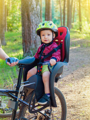 Baby sitting in a bicycle chair, cycling with children, children's safety on the road, family walks, selective focus