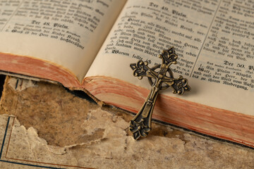 Open vintage holy bible with german text in old print and metal catholic cross with crucifix and...