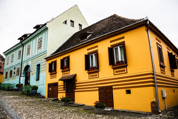 Fototapeta na wymiar Old medieval street with colorful houses. Georgius Krauss House - restaurant and hotel. Sighisoara, Romania.