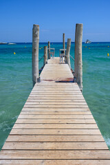 Wooden pier and crystal clear blue water of legendary Pampelonne beach near Saint-Tropez, summer...