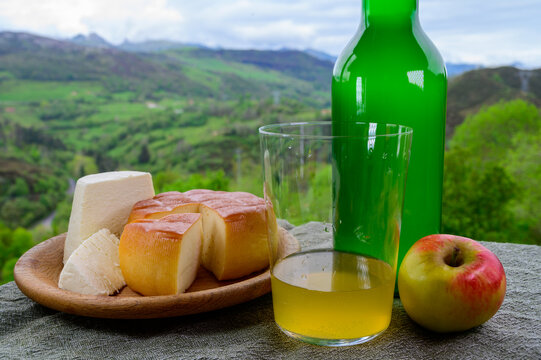 Spanish apple cider, Afuega'l pitu unpasteurised cow's milk cheese and smoked cow milk cheese From Pria, Asturias served outdoor with apples and view on slopes of Picos de Europa mountains