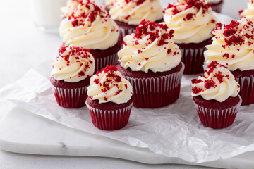 Red velvet cupcakes with cream cheese frosting on a marble board