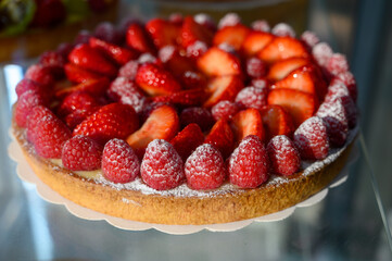 French fresh baked sweet pastry with fresh red summer fruits and berries in confectionery shop close up