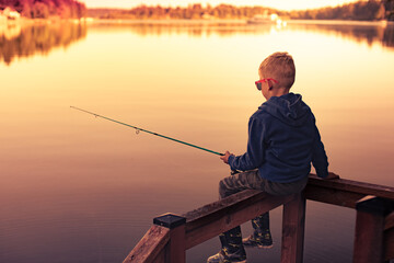 Young boy fishing on a lake at sunset 
