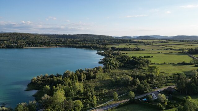 Lac paisible bord&eacute; d'arbres et de prairies au soir, vue a&eacute;rienne