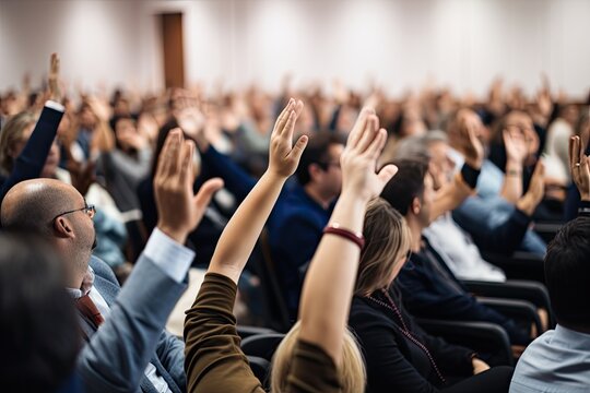 A Diverse Group Of Professionals Attend A Business Seminar And Raise Their Hands To Vote.