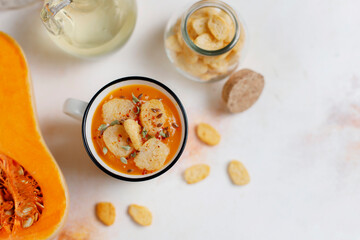 Roasted butternut squash soup with cream and pumpkin seeds on two white mugs.