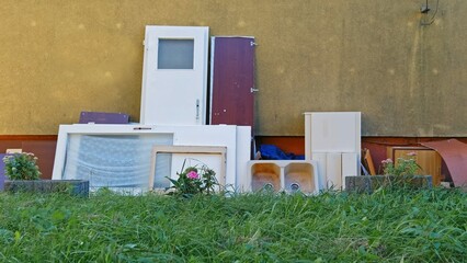 Old Doors and Furniture From Renovated Apartment Dumped at Backyard by Building Wall 