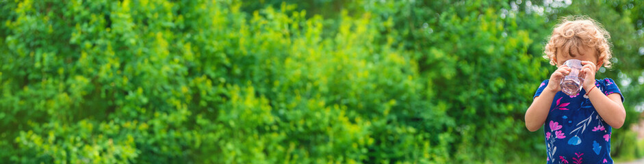 Obraz premium A child drinks water from a glass. Selective focus.