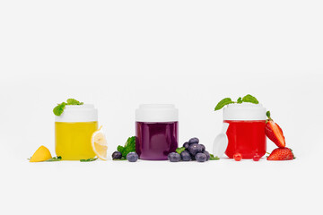Fruity assorted jelly in a jar with fresh strawberry, blueberry, lemon and mint. Mockup dessert. Healthy food. Close-up colorful jelly on white background. Free space for text
