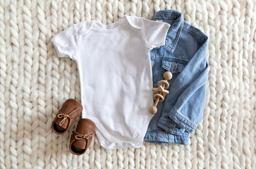 Baby onesie flat lay on a soft background with denim jacket, shoes . Baby bodysuit mockup. Copy...