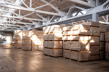Industrial warehouse with stacked wooden planks and finished wood products ready for distribution