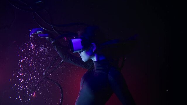 Beautiful woman with flowing hair in futuristic dress under the water. Girl in glasses of virtual reality. Augmented reality, game, future technology concept. VR.