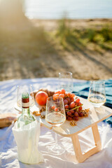 Beautiful cozy autumn picnic by the lake with fruits, pastries and wine. Sun rays. Sunset.