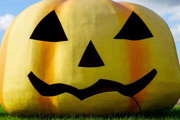 A giant fiberglass Halloween style pumpkin head with a smiley face under the open sky