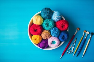 A collection of knitting supplies on a blue surface. The bowl contains yarn and needles while a crochet hook and more yarn lie beside it. Generative AI - obrazy, fototapety, plakaty
