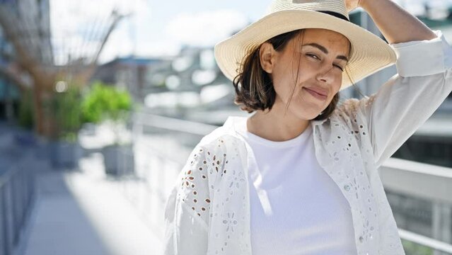 Beautiful young hispanic woman smiling confident wearing summer hat in the streets of Stockholm