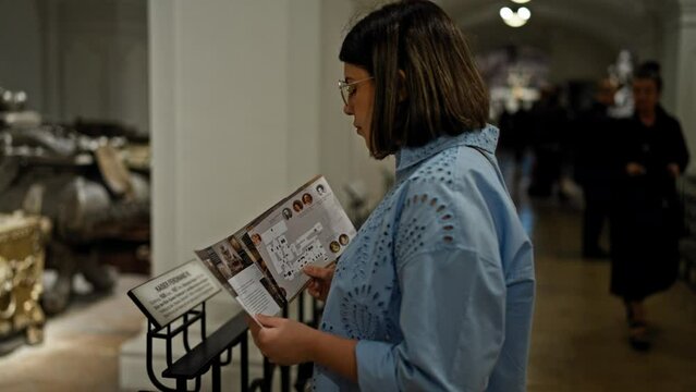 Young beautiful hispanic woman visiting crypt reading brochure at Imperial Crypt in Vienna