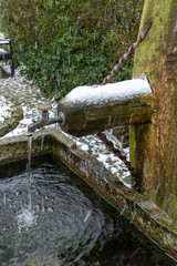 Antique bronze water faucet outside during snowfall