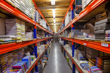 heavy duty shelves in a warehouse filled with books and paper rims for school and stationary...