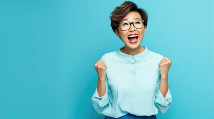 Foto op Plexiglas Beautiful middle age asian business woman winner wearing business clothes celebrating excited for success with arms raised . winner concept. Blue wall © Synthetica