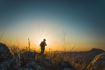 Silhouette of a young boy standing with the sun in the background of the scene at sunset in the hills in Subbetic Mountains in Cordoba, Spain