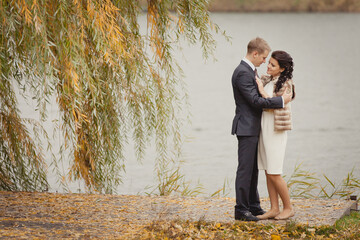 Romantic autumn wedding. Couple of young man and woman on autumn walk outdoors. Two lovers in a fall park. Love and tender touch. Autumn wedding. Rainy autumn wedding day. Yellow fall. 