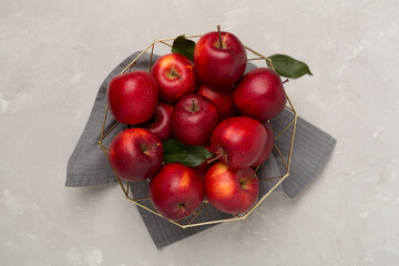 Fresh red apples with leaves on concrete background, top view