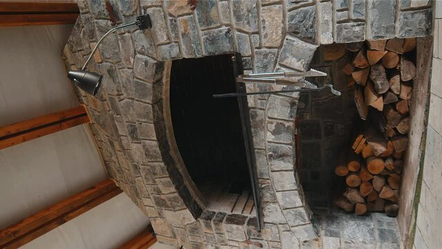 Stone barbecue firewood, open brick oven for cooking kebabs and other dishes on fire indoors in backyard. Restaurant kitchen, pizza oven, bar-b-q grill. Cooking food. Interior construction. Vertical