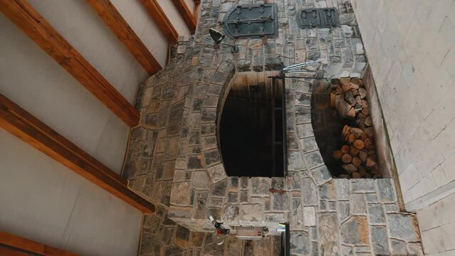 Stone barbecue firewood, open brick oven for cooking kebabs and other dishes on fire indoors in backyard. Restaurant kitchen, pizza oven BBQ grill. Cooking food. Interior modern construction. Vertical