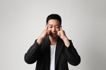 Stressed young Asian man cover his ears with hands, posing over white background