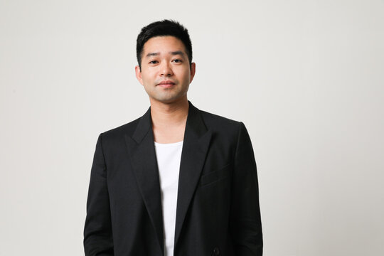 Handsome young Asian man in black suit posing indoor. Horizontal mock-up.