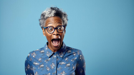 Shocked old senior african american woman wearing casual clothes isolated on blue background amazed and surprised looking at camera - obrazy, fototapety, plakaty