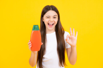 Teenager child girl showing bottle shampoo conditioners or shower gel. Hair cosmetic product. Bottle for advertising mock up copy space. Excited teenager, glad amazed and overjoyed emotions.