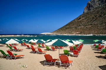 Umbrellas and sunbeds on the sandy beach in Stavros on the island of Crete