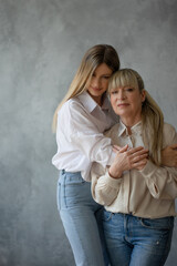 Happy family, women together. Mom and adult daughter smile at each other, studio photo in casual style
