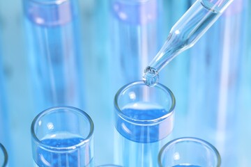 Dripping reagent into test tube on blurred background, closeup. Laboratory analysis