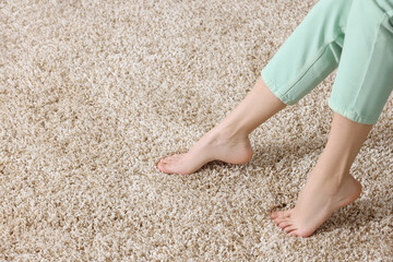 Woman on soft light brown carpet at home, closeup. Space for text
