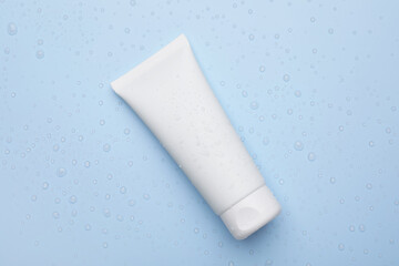 Wet tube of face cleansing product on light blue background, top view