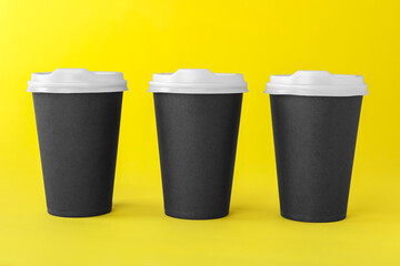 Paper cups with white lids on yellow background. Coffee to go